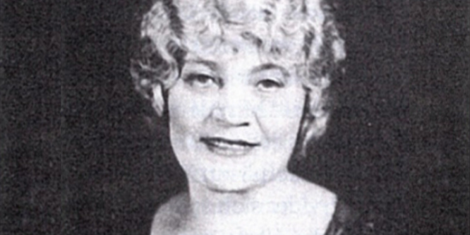 Abbildung einer älteren Dame mit welligen Haaren und Kleid in schwarz-weiß.